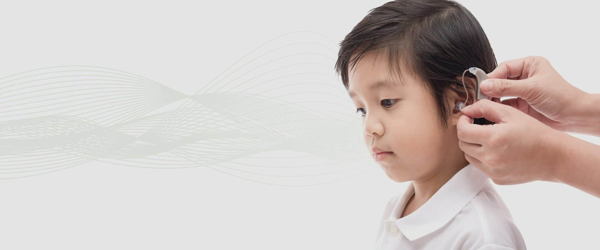 Close-up of young boy being fitted with a hearing aid (ANURAK PONGPATIMET/Shutterstock.com)