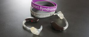 Photo of hearing aids with Alport syndrome awareness bracelet