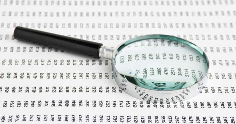 Photo of a magnifying glass laid on a sheet of codes