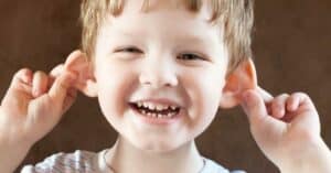 Portrait photo of young boy holding his ears out