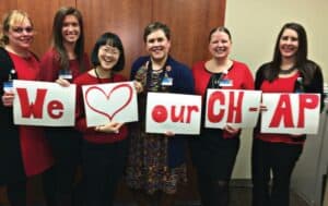 Group of women holding up group of signs that read "We Love Our CH-AP"