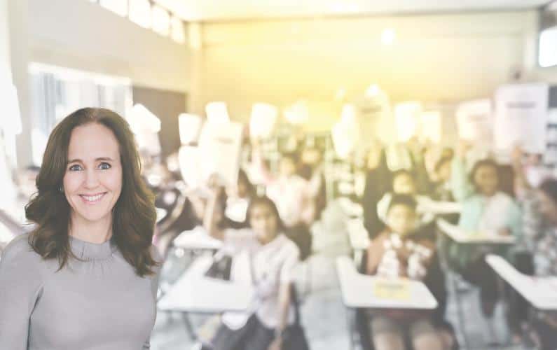 Image of Dana Suskind in front of a blurred classroom full of students