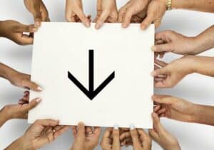 Close-up photo of hands holding sign with arrow pointing downward