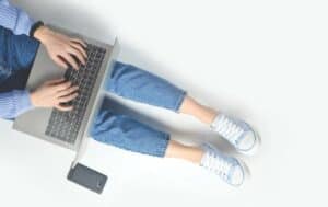 Cropped photo of female student sitting on the floor with her laptop