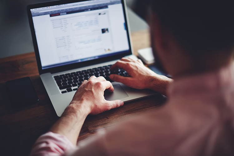 Cropped image of a young man working on his laptop in a coffee shop, rear view of business man hands busy using laptop at office desk, young male student typing on computer sitting at wooden table