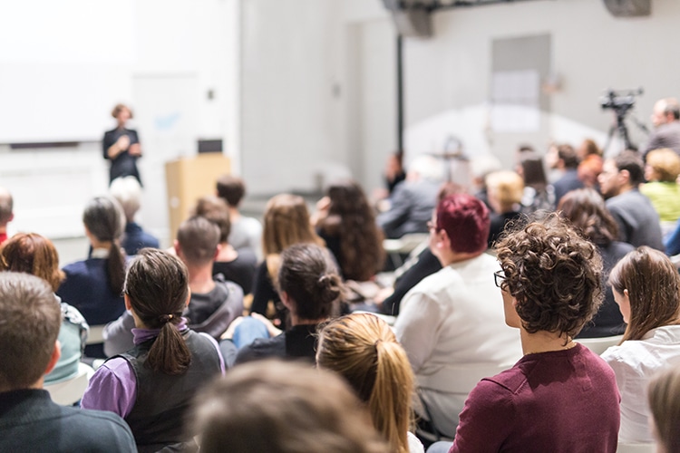 Female,Speaker,Giving,Presentation,In,Lecture,Hall,At,University,Workshop. Educational Sessions