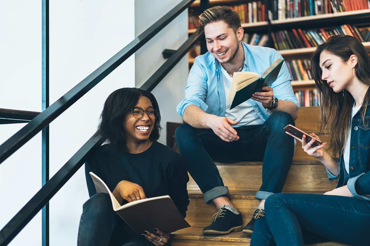 Happy,Youthful,Smart,Diverse,Group,Of,Undergraduates,Enjoying,Studying,During Happy youthful smart diverse group of undergraduates enjoying studying during exam preparation while sitting together on stairs in college library