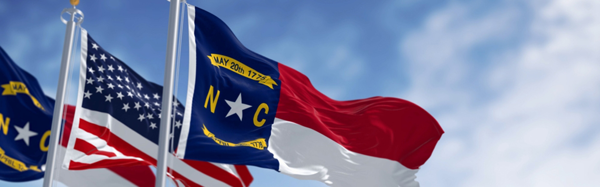 North Carolina state flags waving with american flag. North Carolina is a state in the Southeastern region of the S. Rippled fabric.