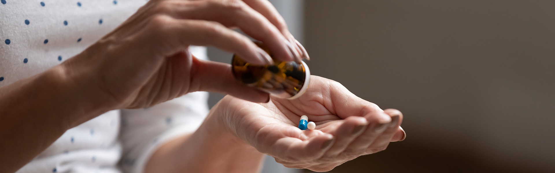 Close up 60s old woman pours out from bottle pills time to take medicaments / shutterstock.com
