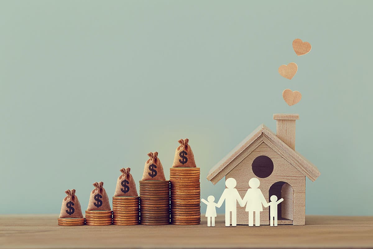 Mini,House,And,Heart,,Family,Members,,Us,Money,Bags,On Mini house and heart, family members, US money bags on rows of rising coins on table. Family tax benefit, residential property tax concept: depicts home equity loan, real estate business investment.