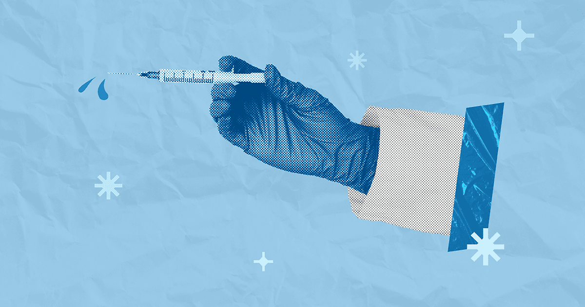 Hand wearing latex glove holding syringe filled with vaccine.