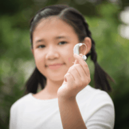 Out-of-focus image of an asian girl holding up a hearing aid